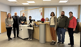 Sieben Personen stehen vor der neuen Infotheke im Neuen Rathaus