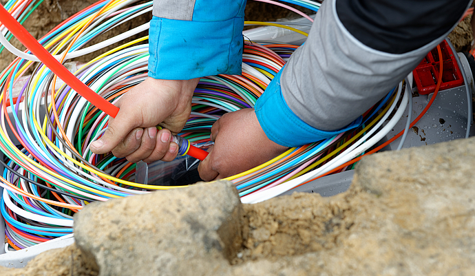 Männerhände, die Kabel im Boden verlegen
