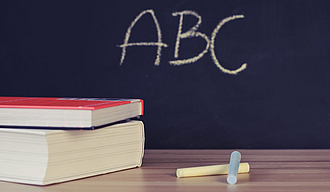 Bücher vor einer Tafel auf der ABC steht